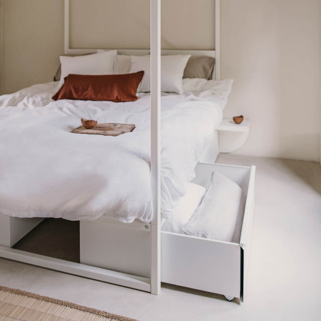 Wit bed stalen frame met lade en kussen en kleed in ruimte - Robuust Amsterdam