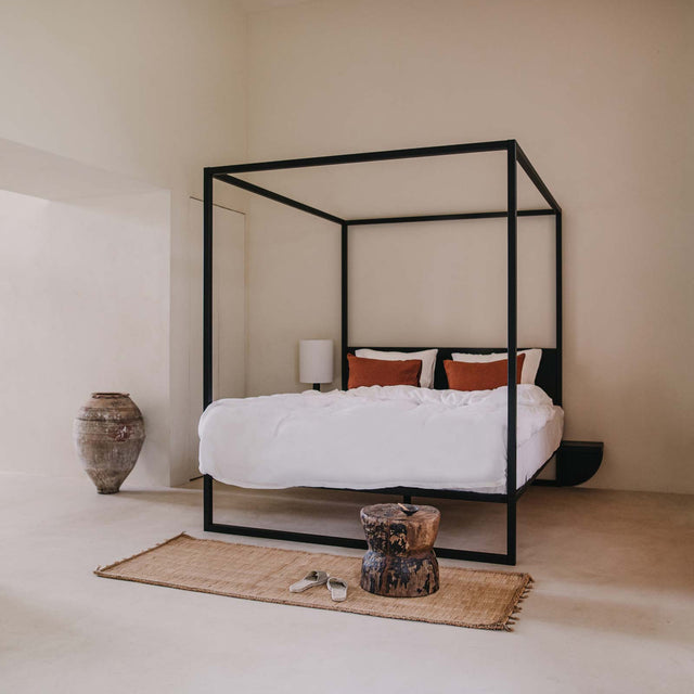 Zwart hemelbed met hoofdbord en nachtplankje in ruimte met vloerkleed - Robuust Amsterdam